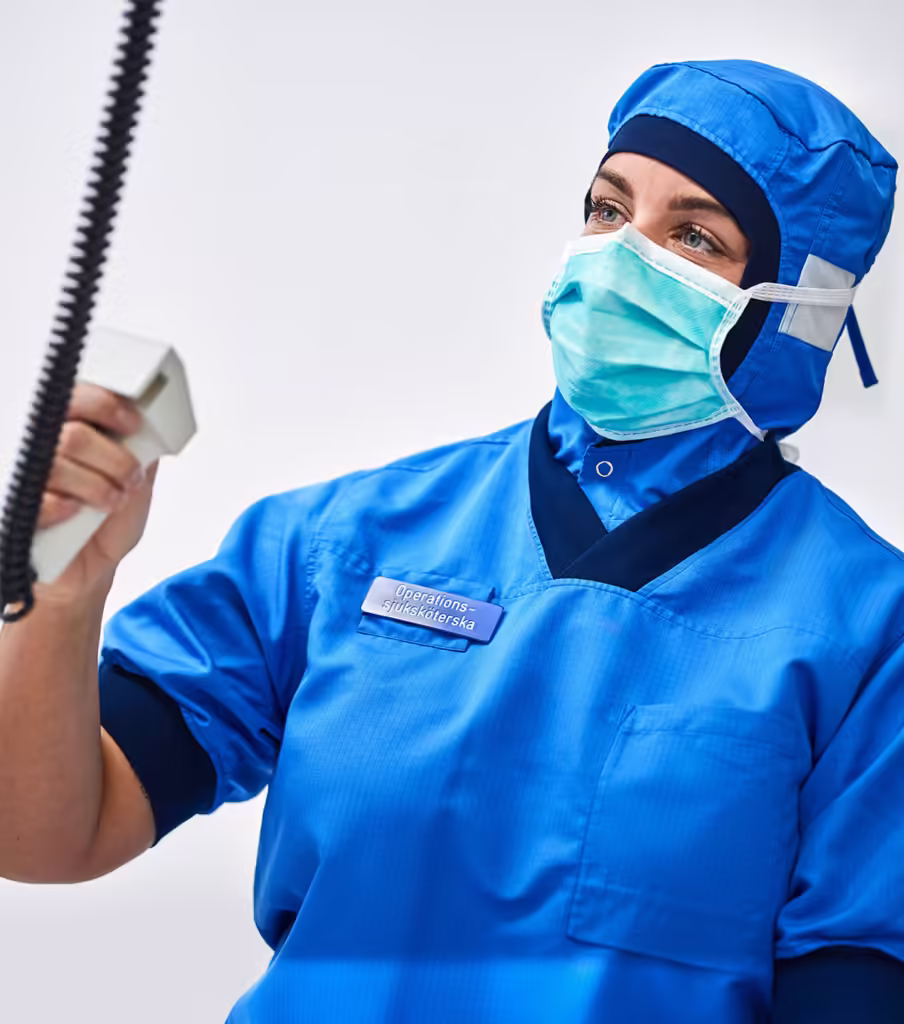 Operationssjuksköterska i en operationssal håller i ett instrument.